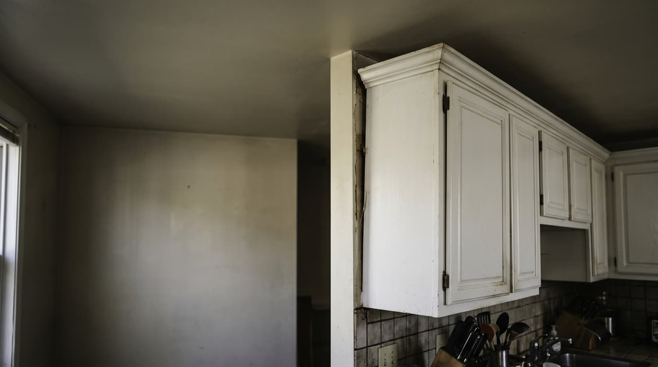 Inspecting a kitchen wall with detached cabinets