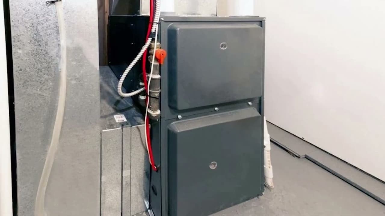 Technician observing a basement utility room with an HVAC furnace.