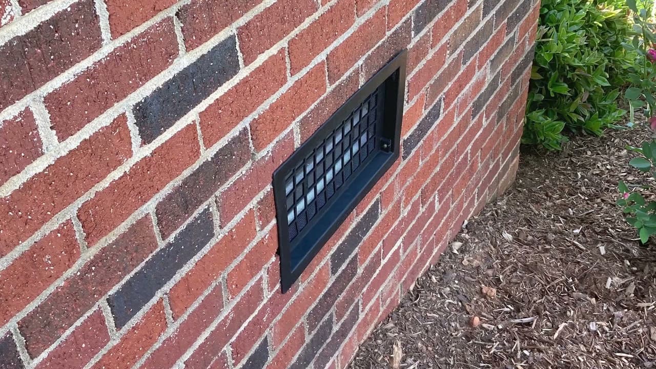 Installing a crawl space vent cover in a brick foundation wall.