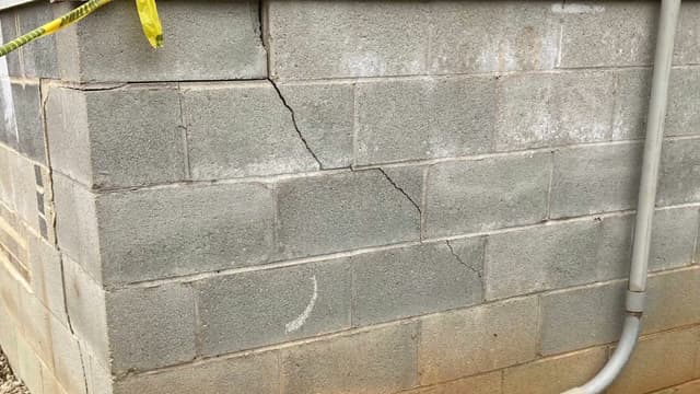 HydroHelp911 Crawl Space & Foundation Repair inspecting stair step cracks, efflorescence on a concrete block foundation wall.