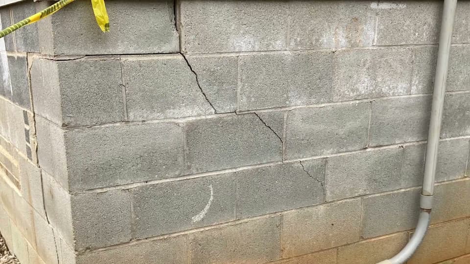HydroHelp911 Crawl Space & Foundation Repair inspecting stair step cracks, efflorescence on a concrete block foundation wall.