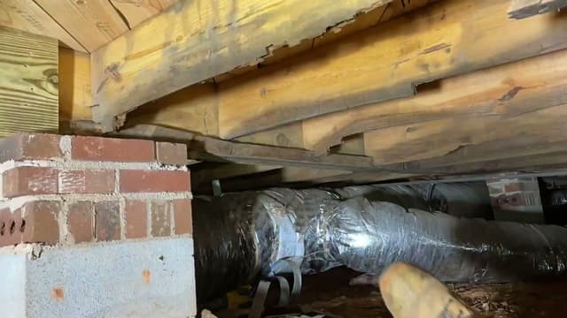 HydroHelp911 Crawl Space & Foundation Repair inspecting damaged floor joists in a crawl space.