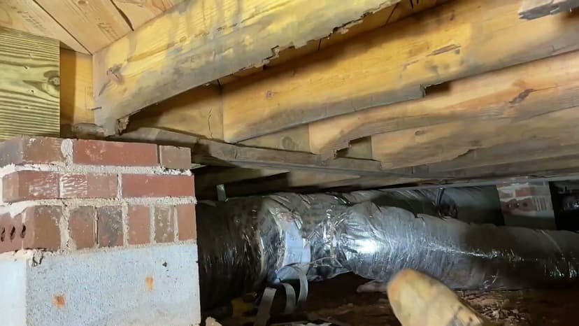 HydroHelp911 Crawl Space & Foundation Repair inspecting damaged floor joists in a crawl space.