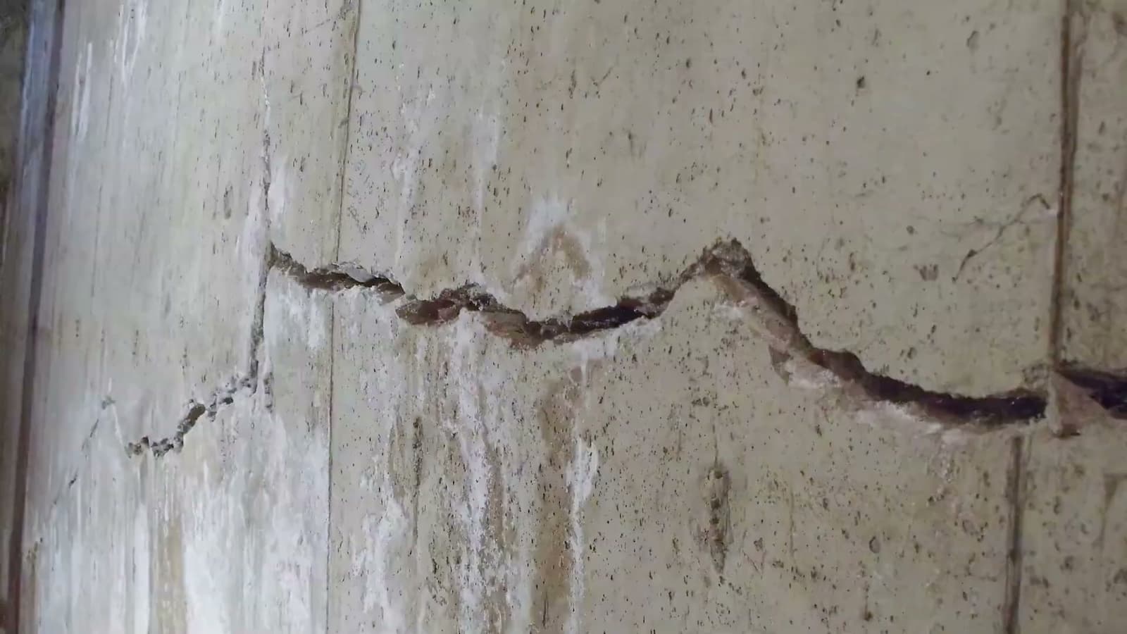 HydroHelp911 Crawl Space & Foundation Repair inspecting large horizontal cracks in a wet concrete basement wall