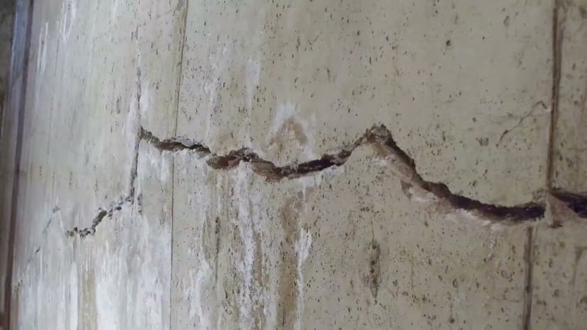 HydroHelp911 Crawl Space & Foundation Repair inspecting large horizontal cracks in a wet concrete basement wall