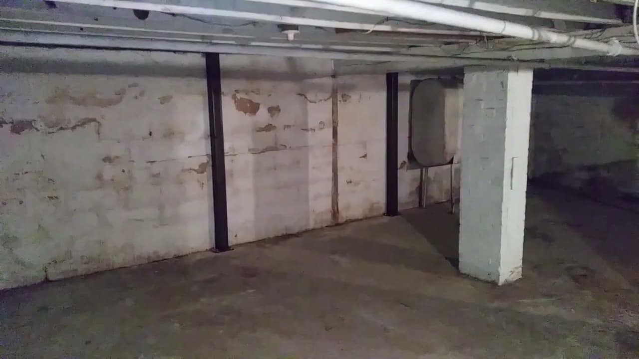 Installing steel I-beam wall bracing in a basement to stabilize cracked walls.