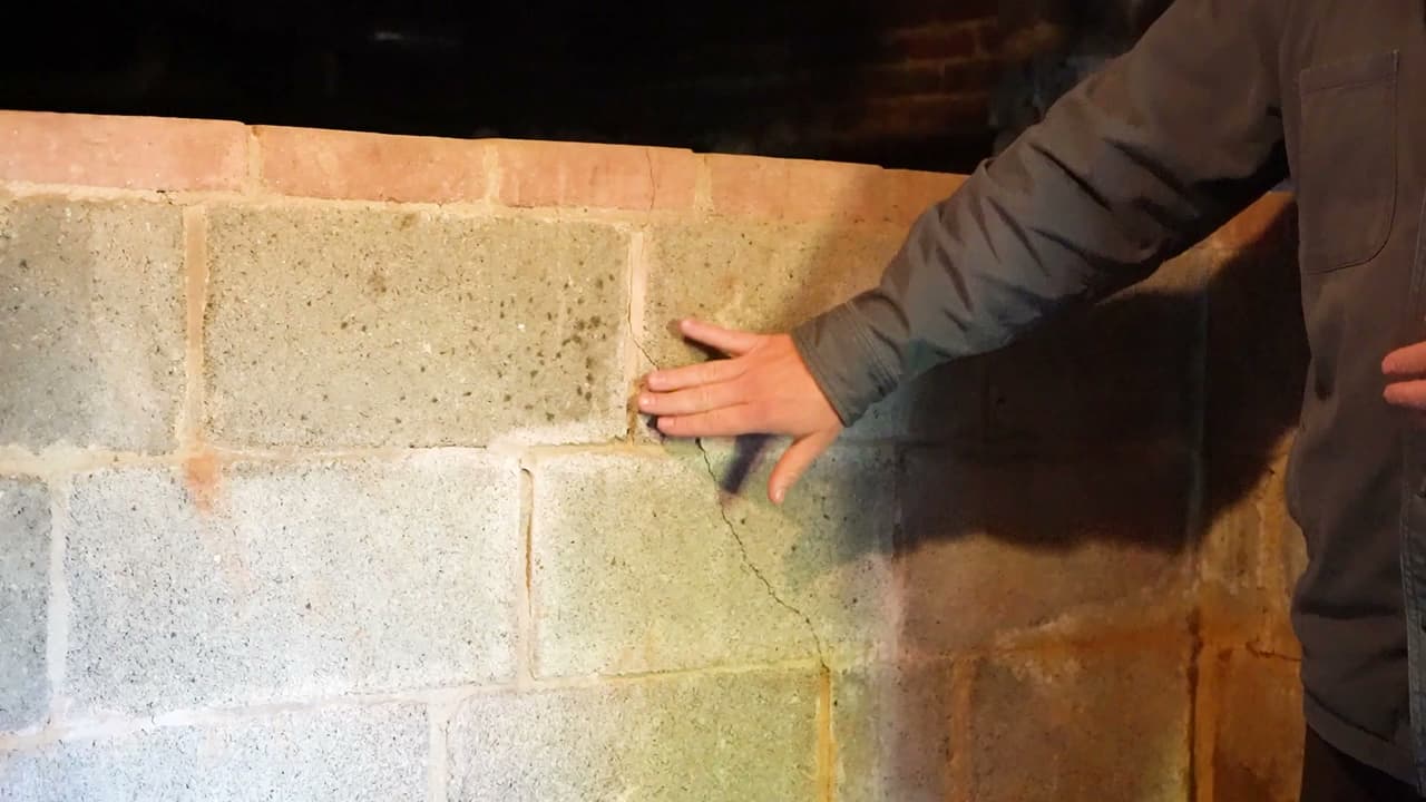 Inspecting a cracked block basement wall caused