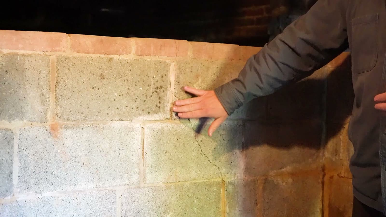 HydroHelp911 Crawl Space & Foundation Repair inspecting a cracked block basement wall caused