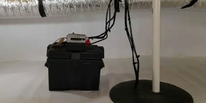 Sump pump discharge pipe and a battery backup box in a basement