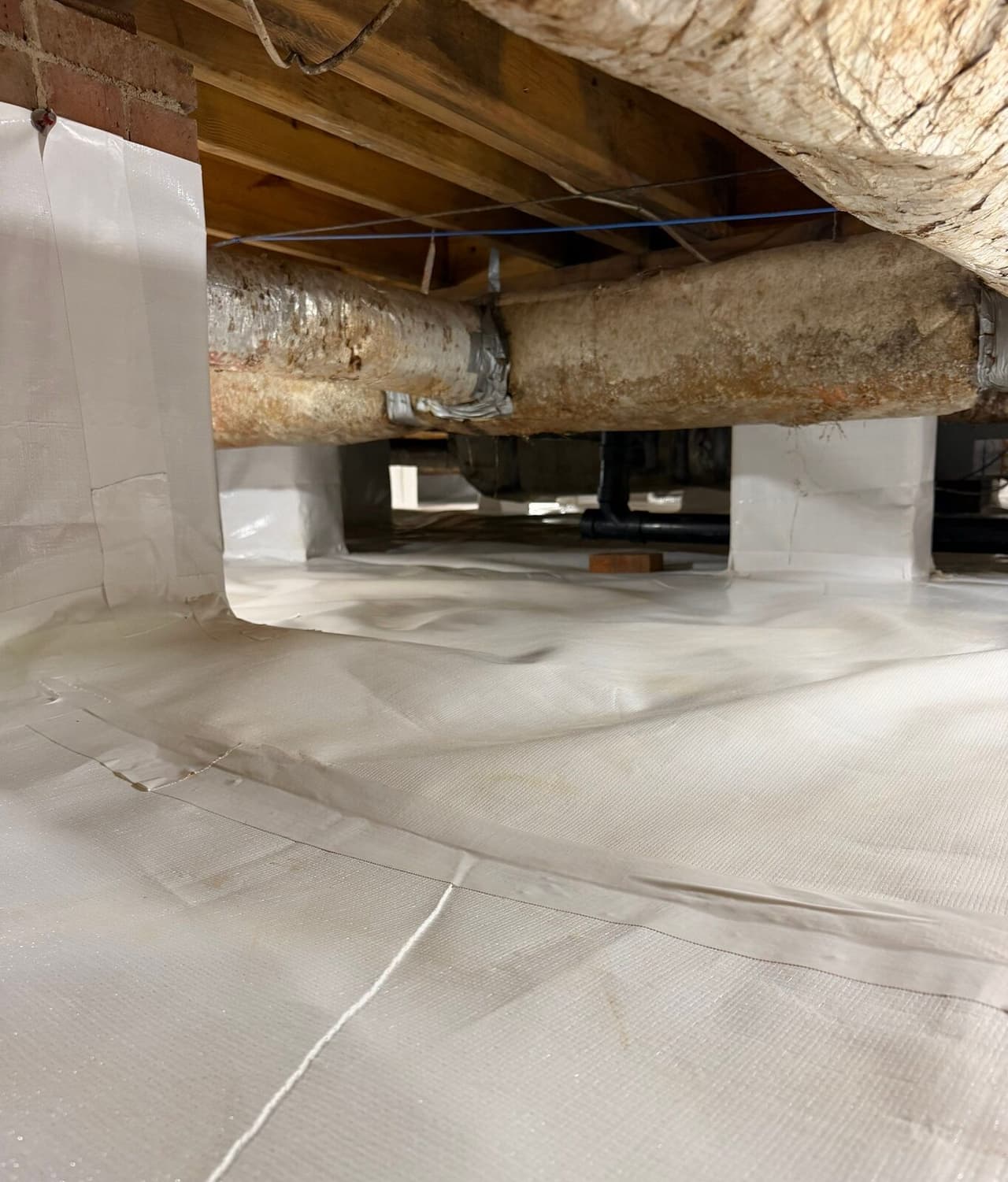 White liner runs up a brick wall and across the floor with wrapped piers behind.