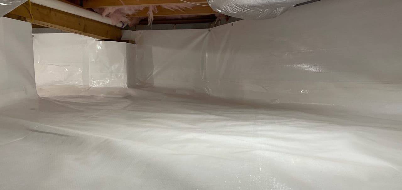 Open crawl space with a white liner covering the floor and the foundation walls.