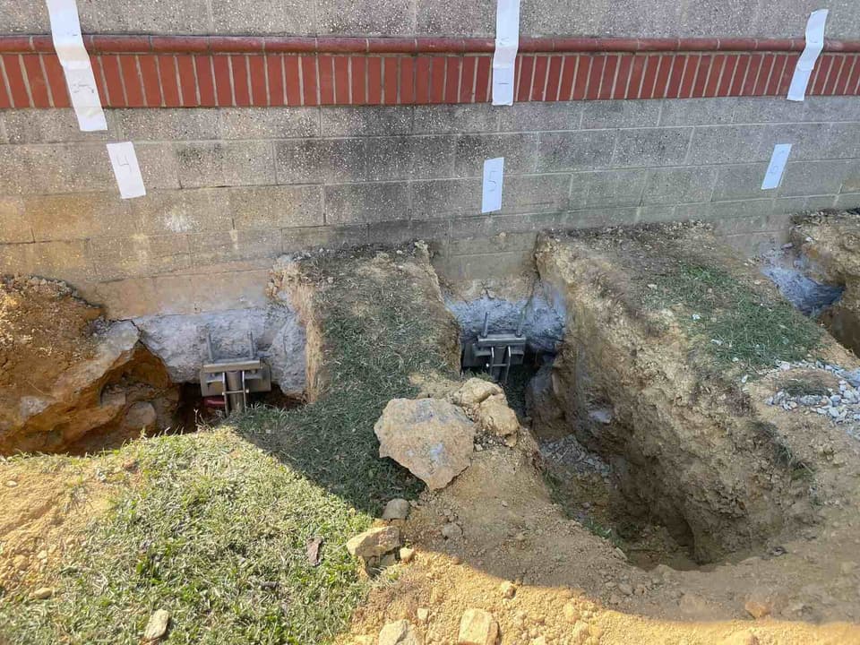 HydroHelp911 Crawl Space & Foundation Repair installing steel piers with footing brackets for foundation stabilization.