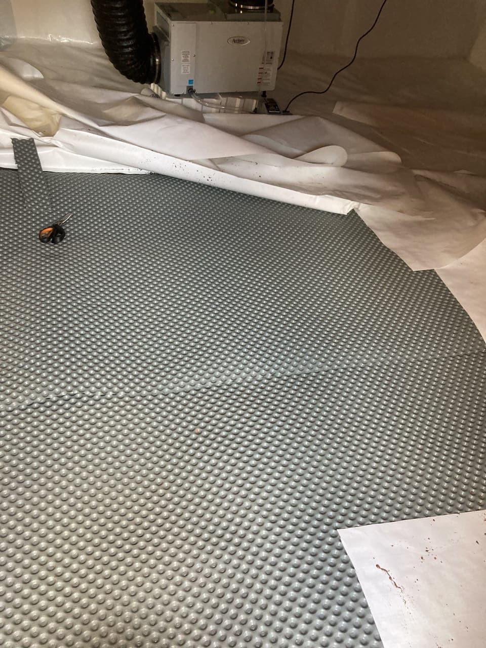 HydroHelp911 Crawl Space & Foundation Repair installing drainage matting for crawl space encapsulation with a dehumidifier.