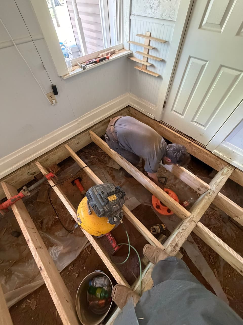 HydroHelp911 Crawl Space & Foundation Repair crew member installing new floor joists and support jacks in a crawl space.