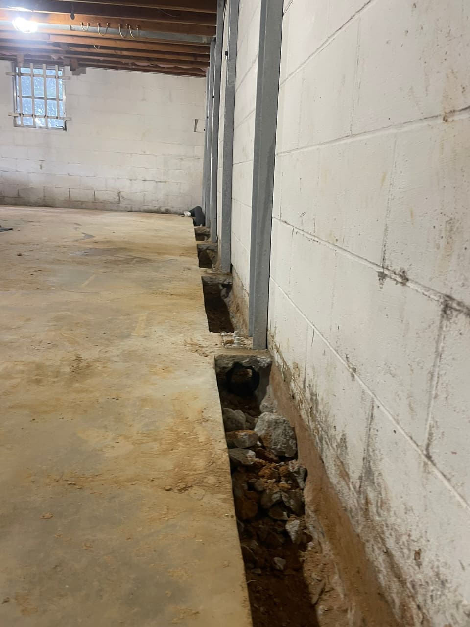 HydroHelp911 Crawl Space & Foundation Repair installing I-beam wall bracing and interior drainage in a basement.