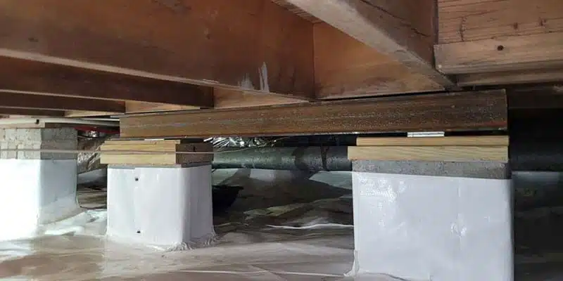 Crawl space piers with wood shims under a floor beam
