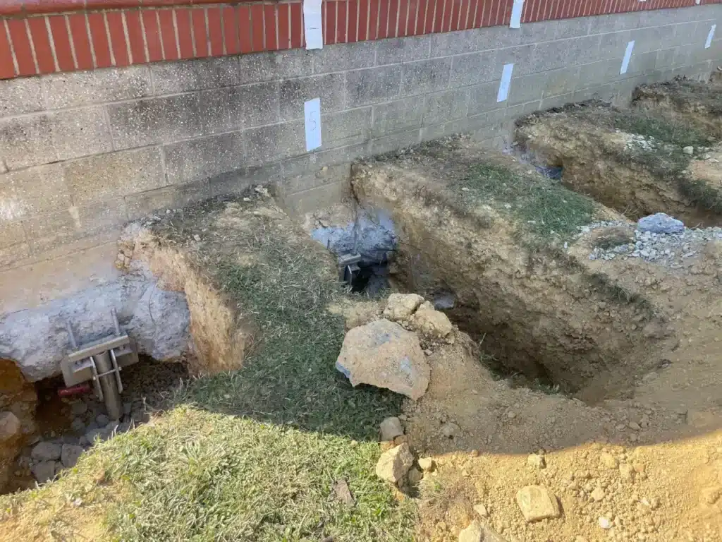 Deep excavation pits along a block foundation wall with steel push piers installed
