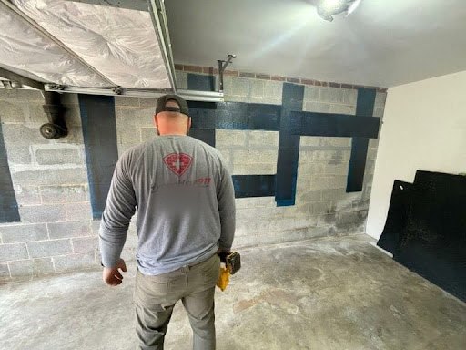 Technician in a basement with carbon fiber straps on a block wall