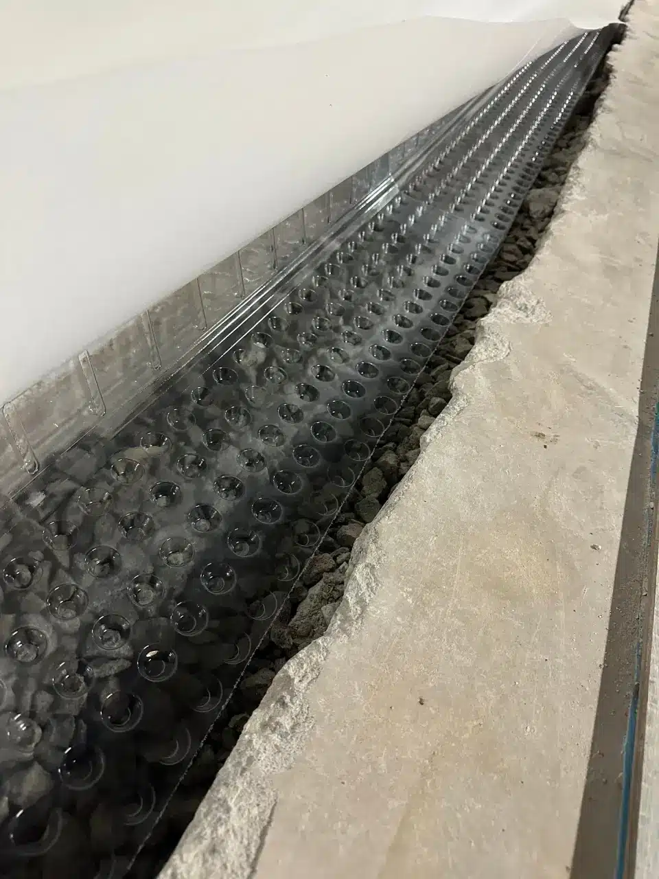 Interior drainage channel being installed along a basement wall