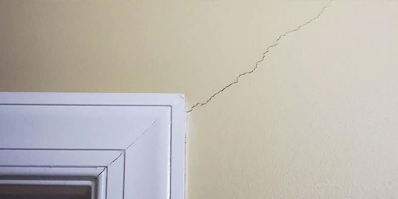 Hairline crack in drywall running from the corner of a window frame