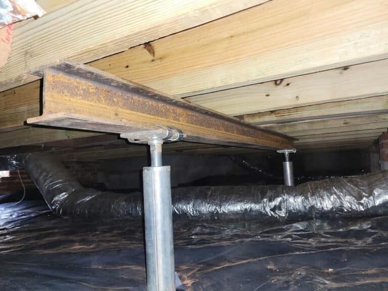 Steel jack posts supporting floor joists in a crawl space