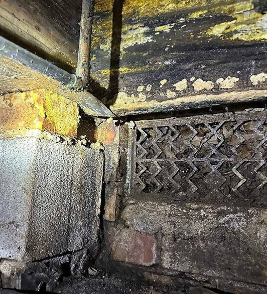 Mold and moisture staining on wood framing beside a crawl space vent