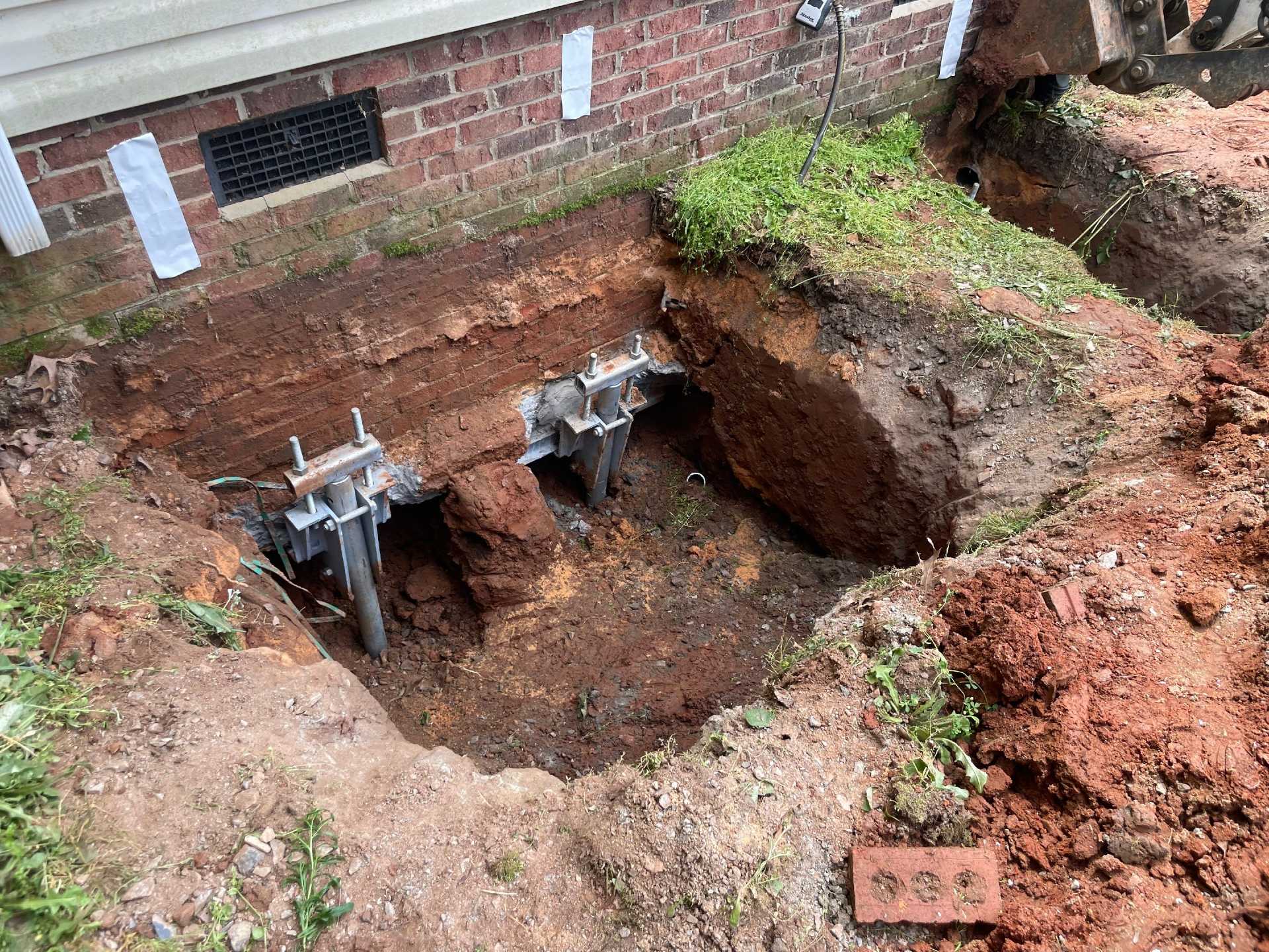Two steel pier brackets at the base of a brick foundation